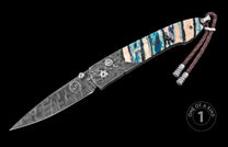 Damascus steel knife with marbled blue and beige handle by Wharncliffe, featuring braided leather lanyard and engraved blade, side view