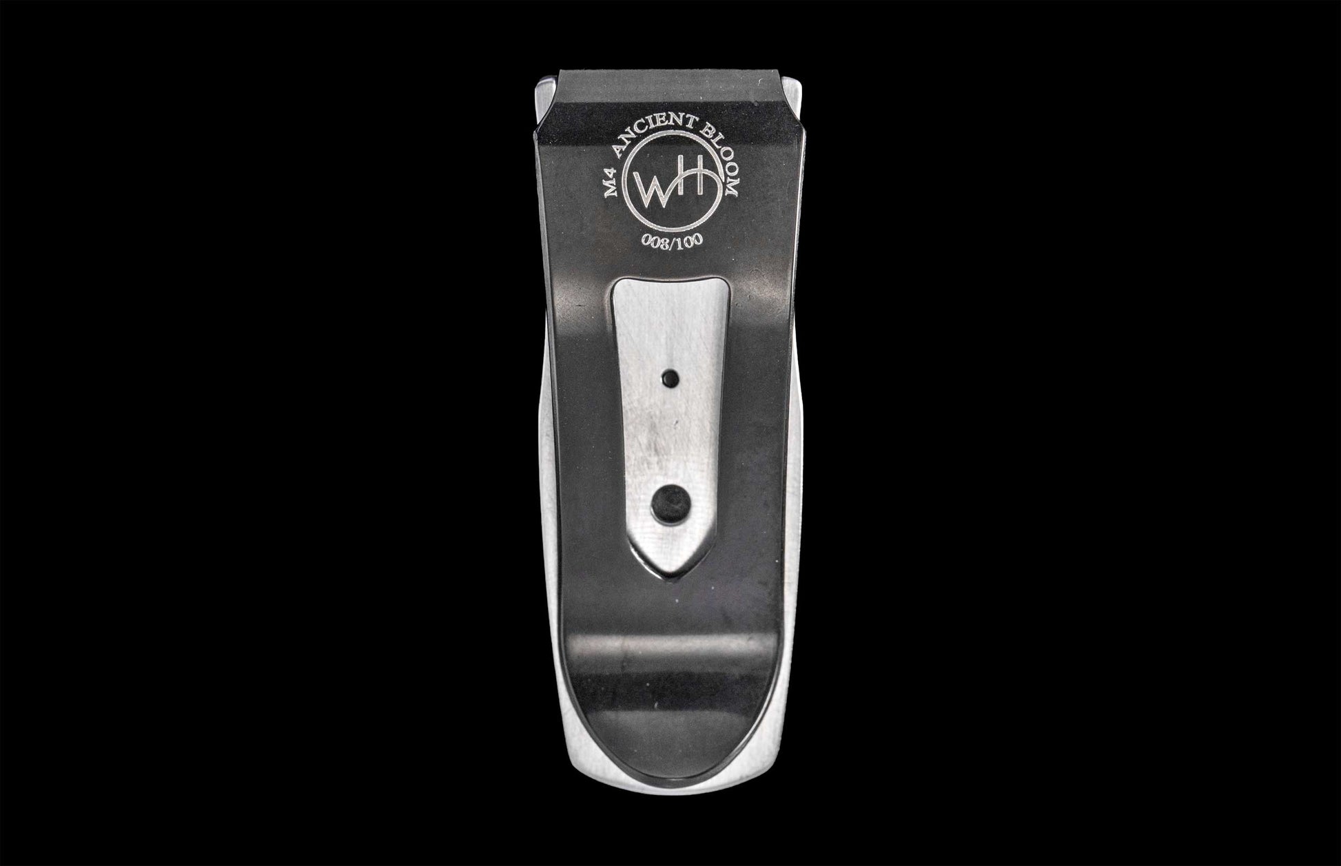 Matte black and brushed silver money clip by M4 Ancient Bloom, engraved with circular logo and limited edition number, front view on black background