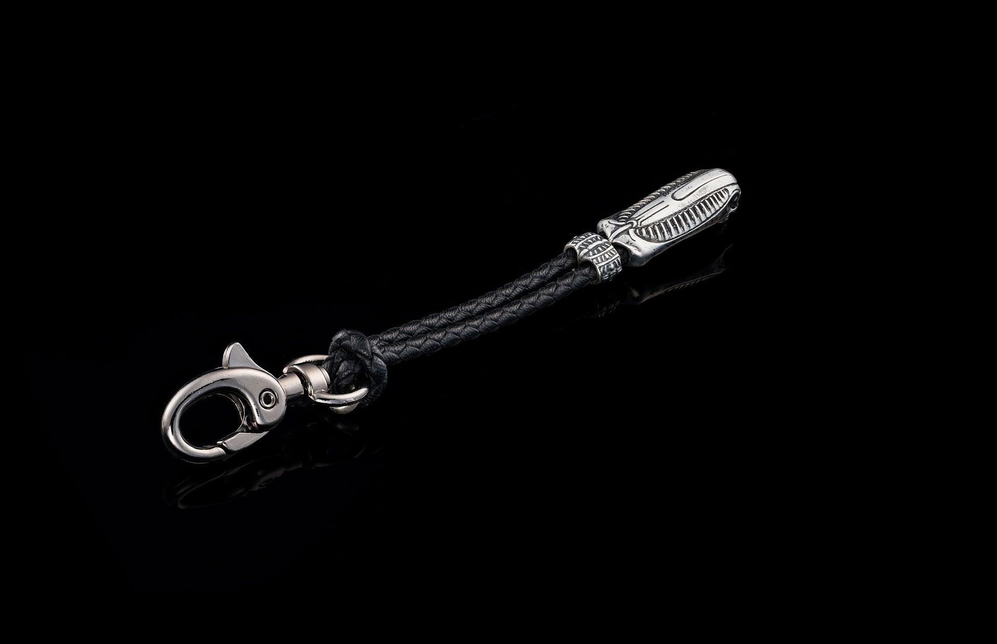 William Henry key fob features a sterling silver skull with Egyptian detailing, a round-braided black leather cord, and a  stainless steel hook 