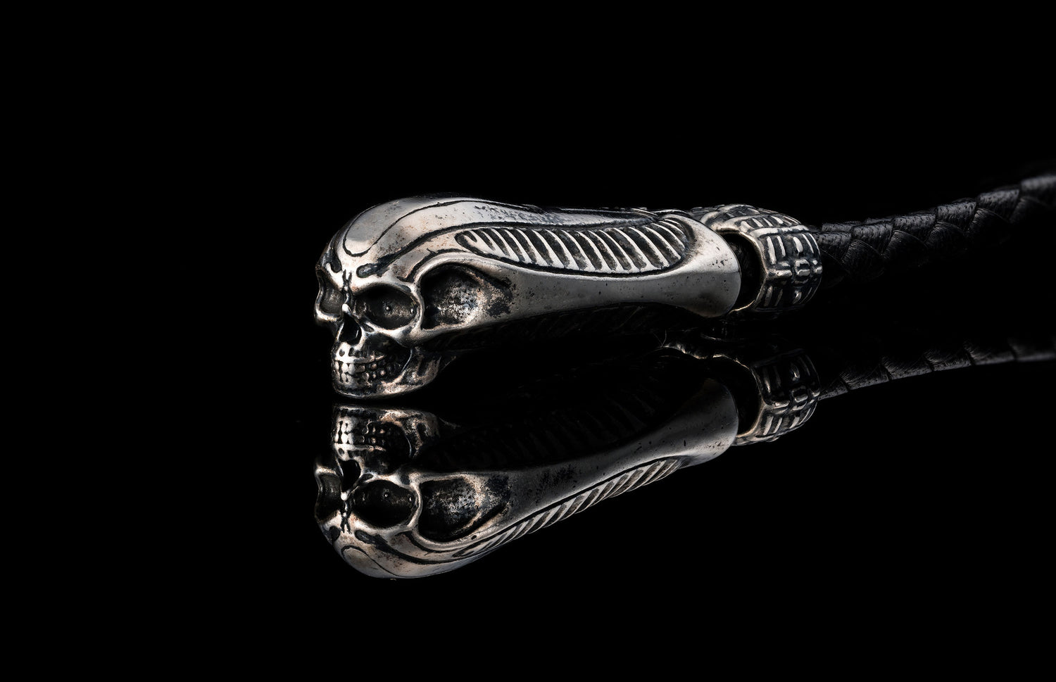 Silver-toned metal key chain by TOUCHSTONE, featuring an ornate skull head with ribbed design and braided black leather.