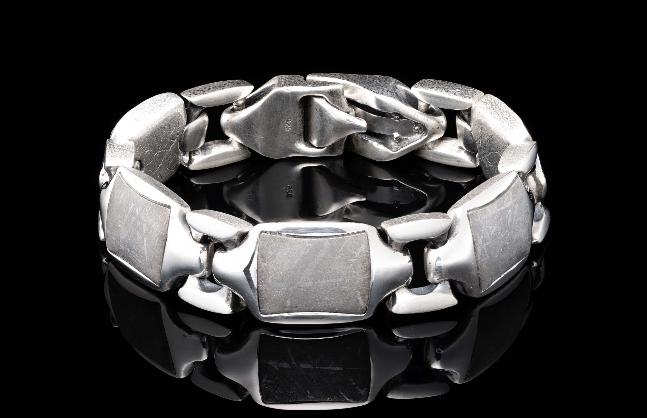 Silver bracelet with chunky links, rectangular meteorite inserts featuring an etched pattern, and a "925" stamp.