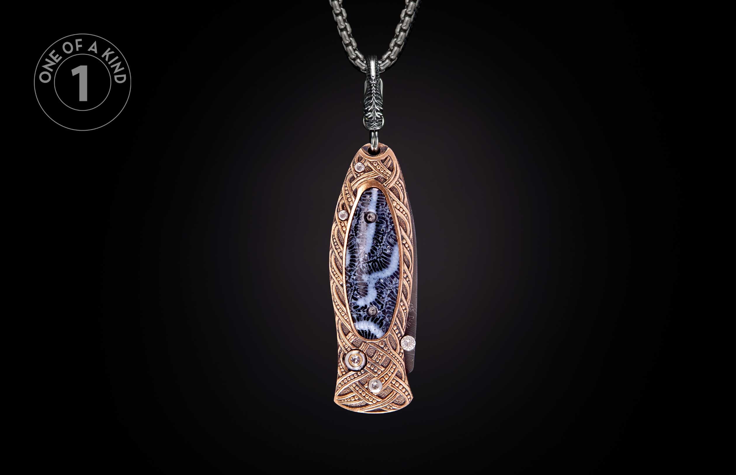 Ornate knife pendant with bronze-toned metal, intricate knotwork, dendritic stone inlay, diamonds, and a silver chain, labeled 'ONE OF A KIND'.