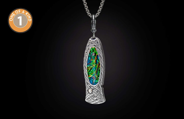 Ornate silver knife with intricate Celtic patterns and iridescent green-blue inlay, accented with clear gems, hanging from a chain.