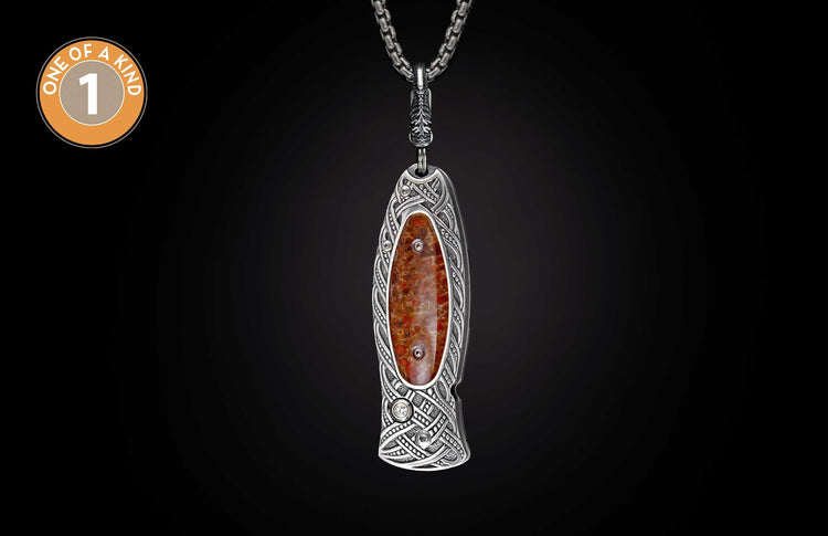 Silver knife pendant with intricate Celtic knotwork, a reddish-brown marbled stone, and small clear accents, hanging from a chain.