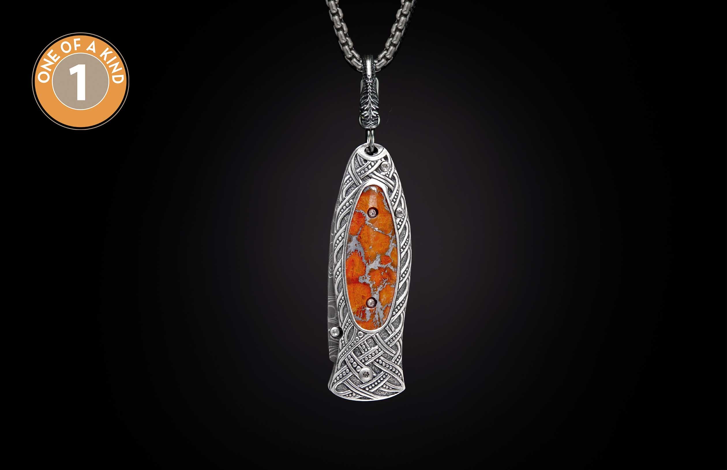 Ornate silver folding knife featuring intricate Celtic knotwork, an orange marbled stone inlay with two small embellishments, and a pocket clip.