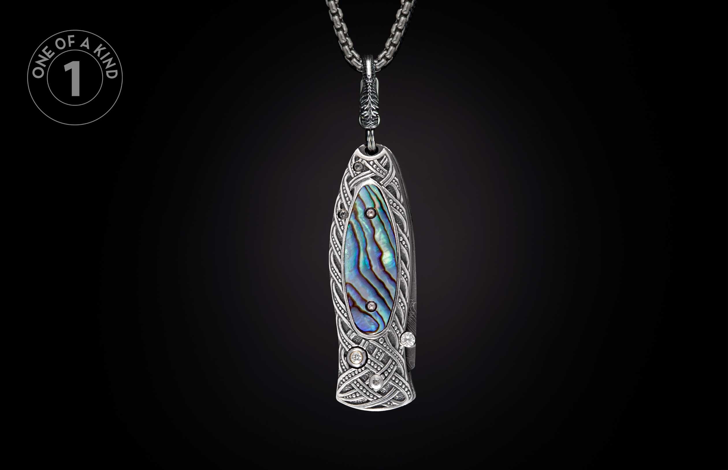 Ornate silver-toned pendant knife with abalone inlay, intricate Celtic knot engraving, and sparkling gemstones.