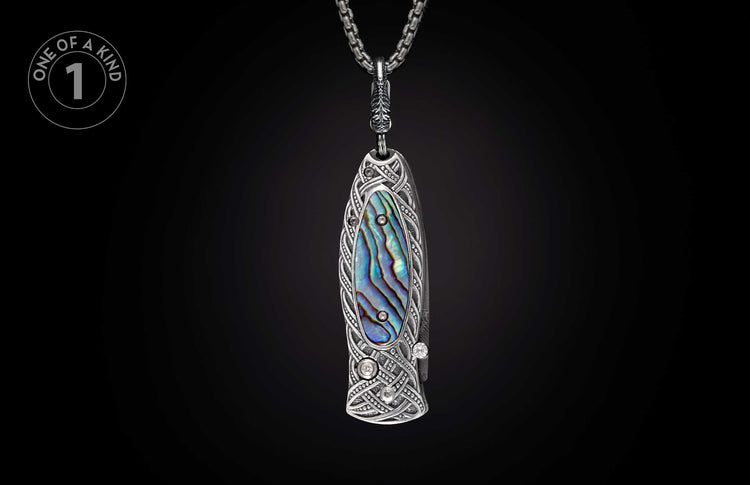 Ornate silver-toned pendant knife with abalone inlay, intricate Celtic knot engraving, and sparkling gemstones.