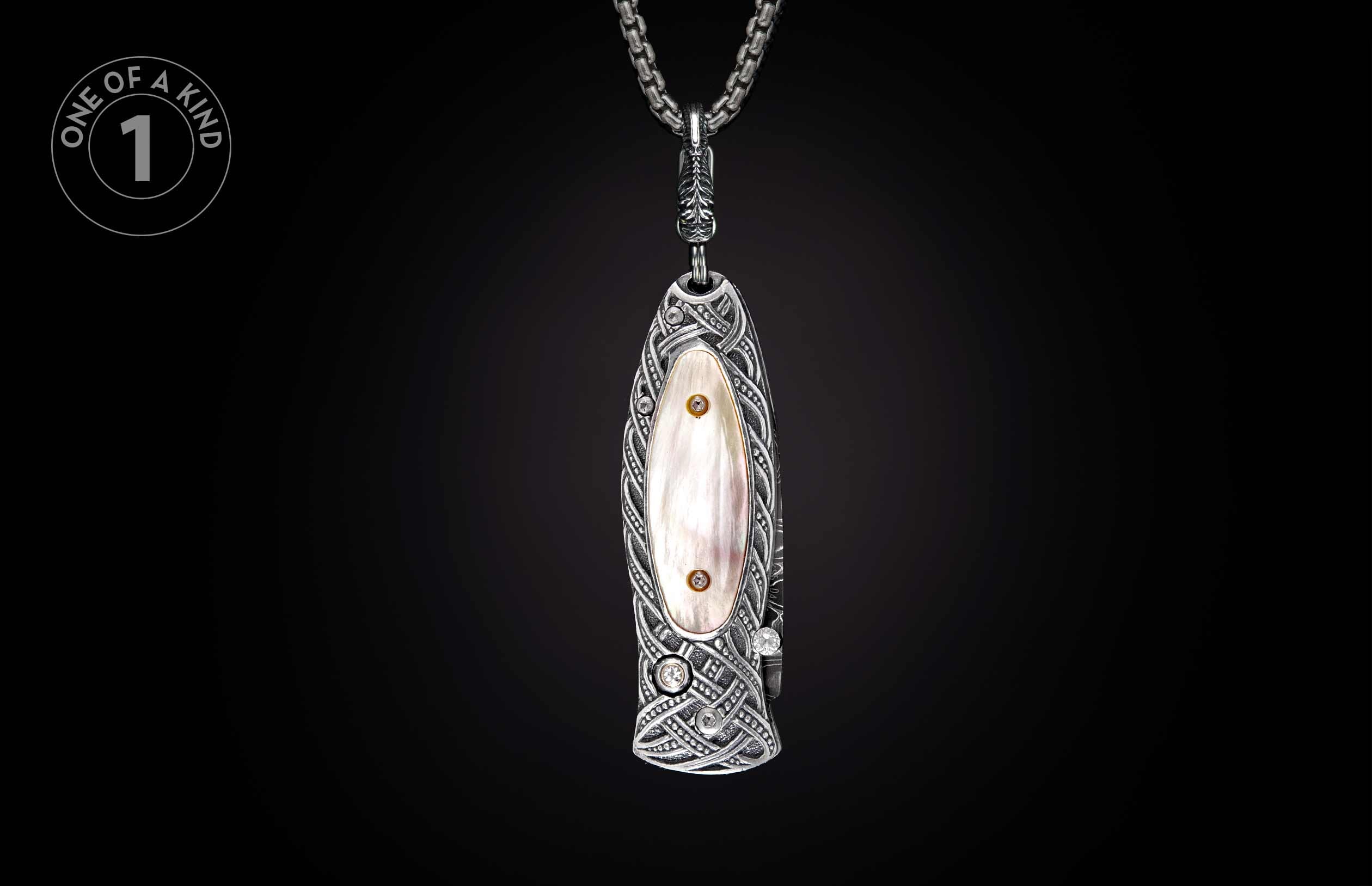 Ornate silver knife pendant with mother-of-pearl, Celtic knot patterns, and clear and gold stones on a chain.