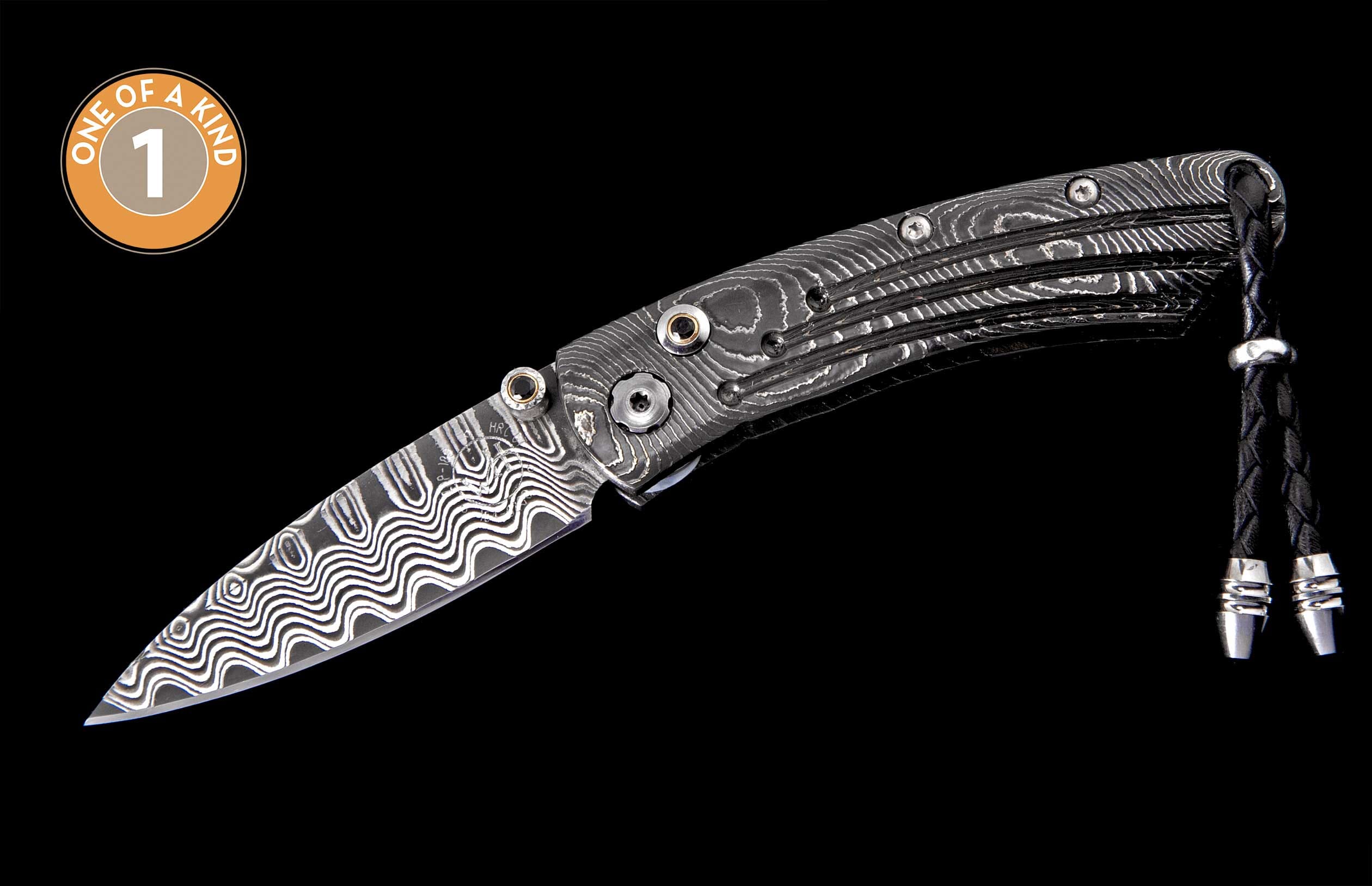 Folding knife with wavy Damascus steel blade and patterned handle, featuring a black braided leather lanyard with silver tips.