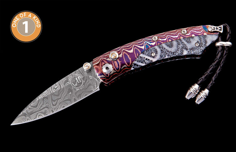 Folding knife featuring a Damascus steel blade, colorful wavy handle with fossilized coral inlay, gem-set pivot, and a black leather lanyard.