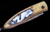 Gold and black ornate knife with a white carved dragon insert, gold leaf engraving, and a patterned Damascus blade.