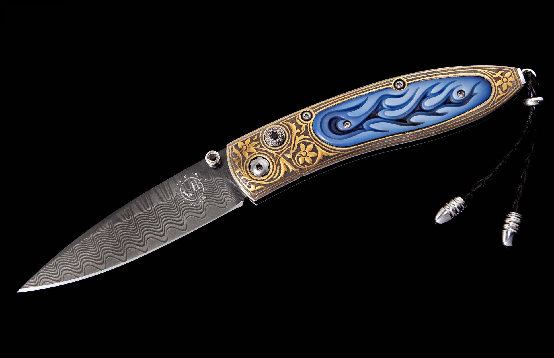 Ornate folding knife featuring a wavy Damascus steel blade, gold floral engraving, blue flame patterns on the handle, and a silver-tipped black lanyard.