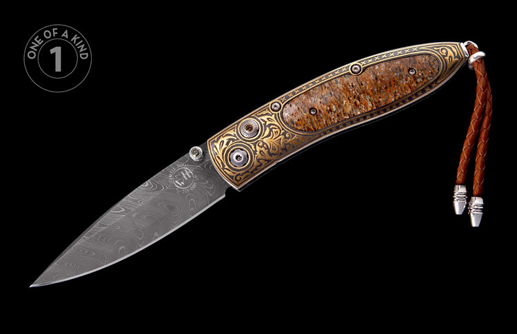 Ornate folding knife with Damascus steel blade, gold engraved handle with mottled inlay, and a brown braided leather lanyard.