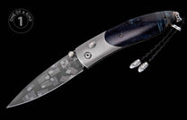 Folding knife with a damascus blade featuring flags and lines, a marbled dark handle with gem-set studs, and a braided lanyard.