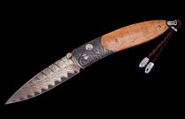 Damascus steel and wood handle folding knife by Hildgund Exclusive with engraved bolsters, yellow jewels, and braided leather lanyard.