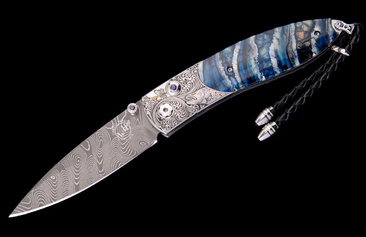 Artistic folding knife with a swirling Damascus blade, intricate silver engraving, and a striking blue, white, and brown layered handle.