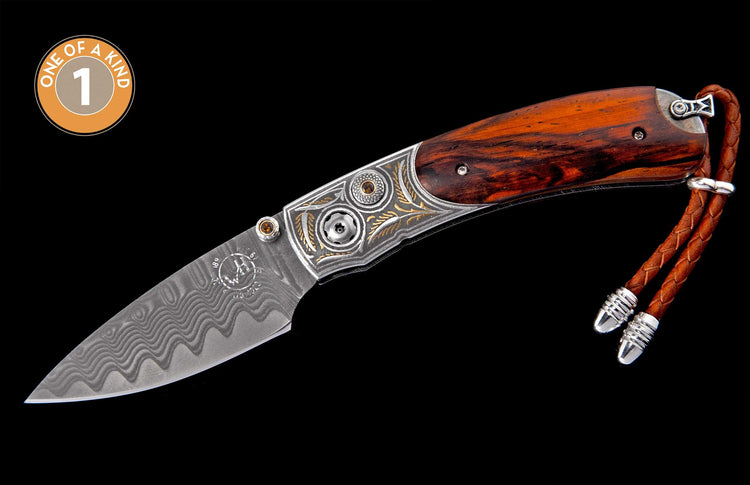 Ornate folding knife with dark wood handle, engraved silver bolster with gold accents, amber gems, wavy Damascus steel blade, and braided leather lanyard.