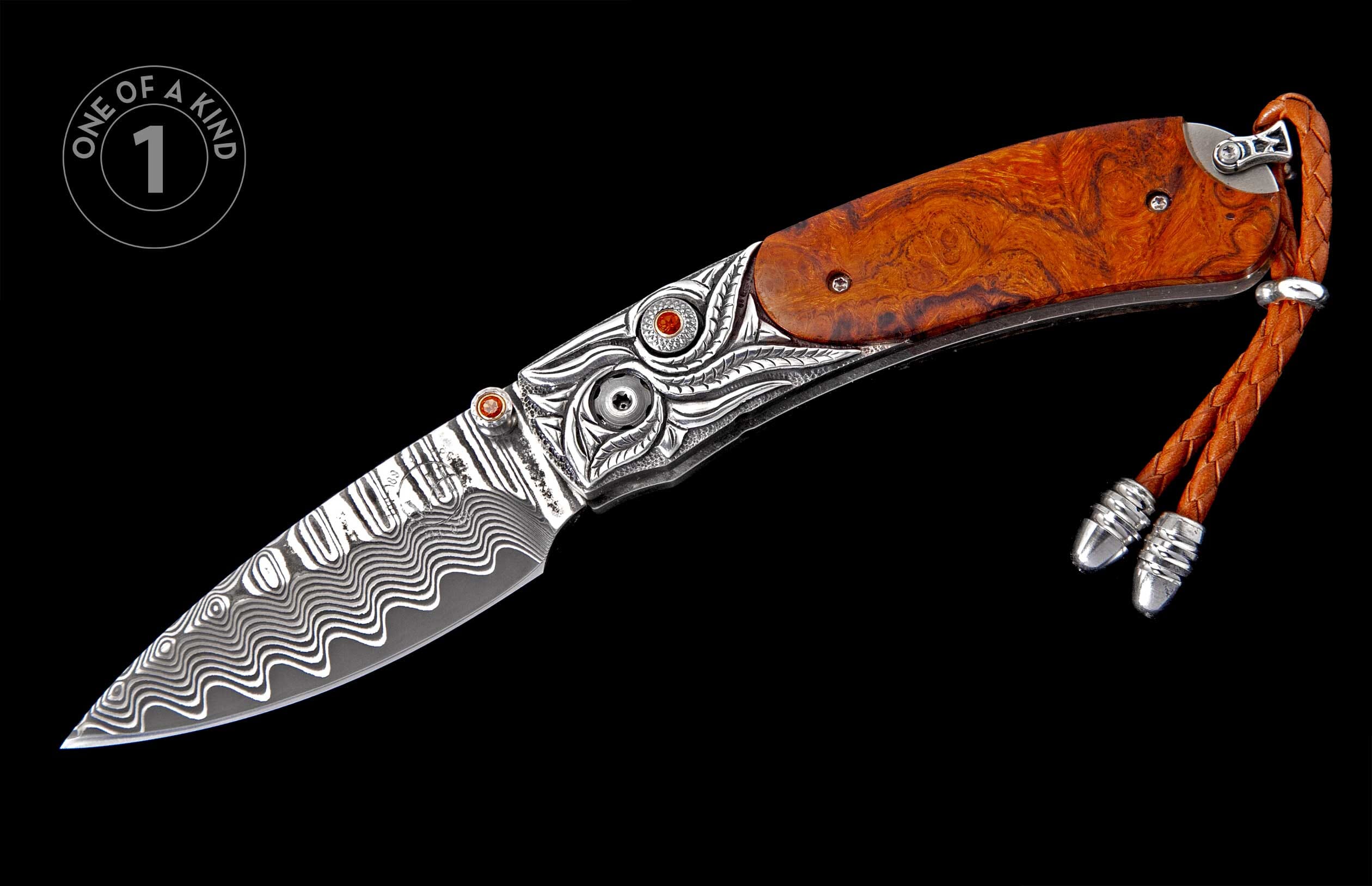 Ornate folding knife with a wavy Damascus blade, burled wood handle, engraved silver bolster featuring orange gems, and braided leather lanyard.
