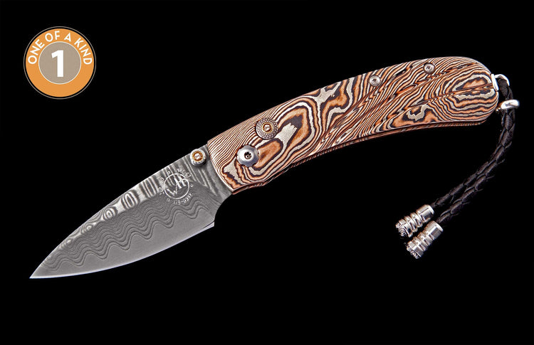 Damascus steel folding knife with wavy patterned blade and copper-toned handle, finished with a black braided leather lanyard.