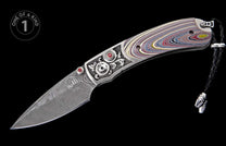 Damascus steel folding knife with a colorful layered handle, ornate silver bolster, red gems, and a braided leather lanyard.