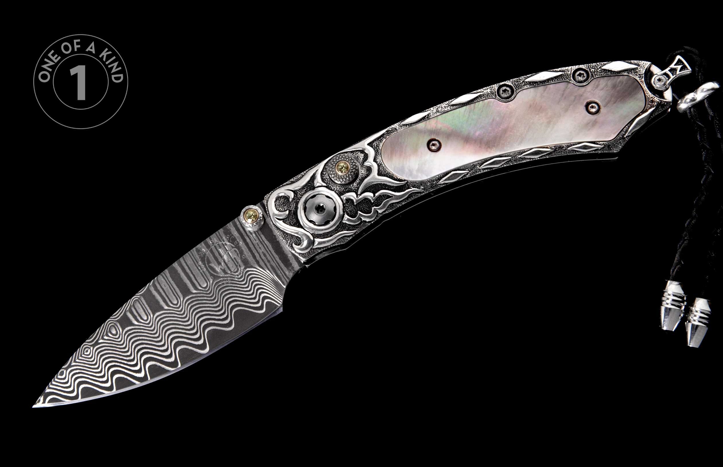 Ornate silver folding knife with a wavy Damascus steel blade, iridescent mother-of-pearl handle, intricate scrollwork, yellow gemstone accents, and a black braided lanyard.
