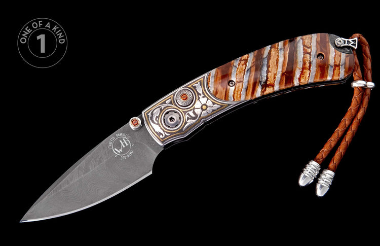 Ornate folding knife with a patterned Damascus blade, engraved frame with gemstones, striped fossil handle, and a braided leather lanyard.