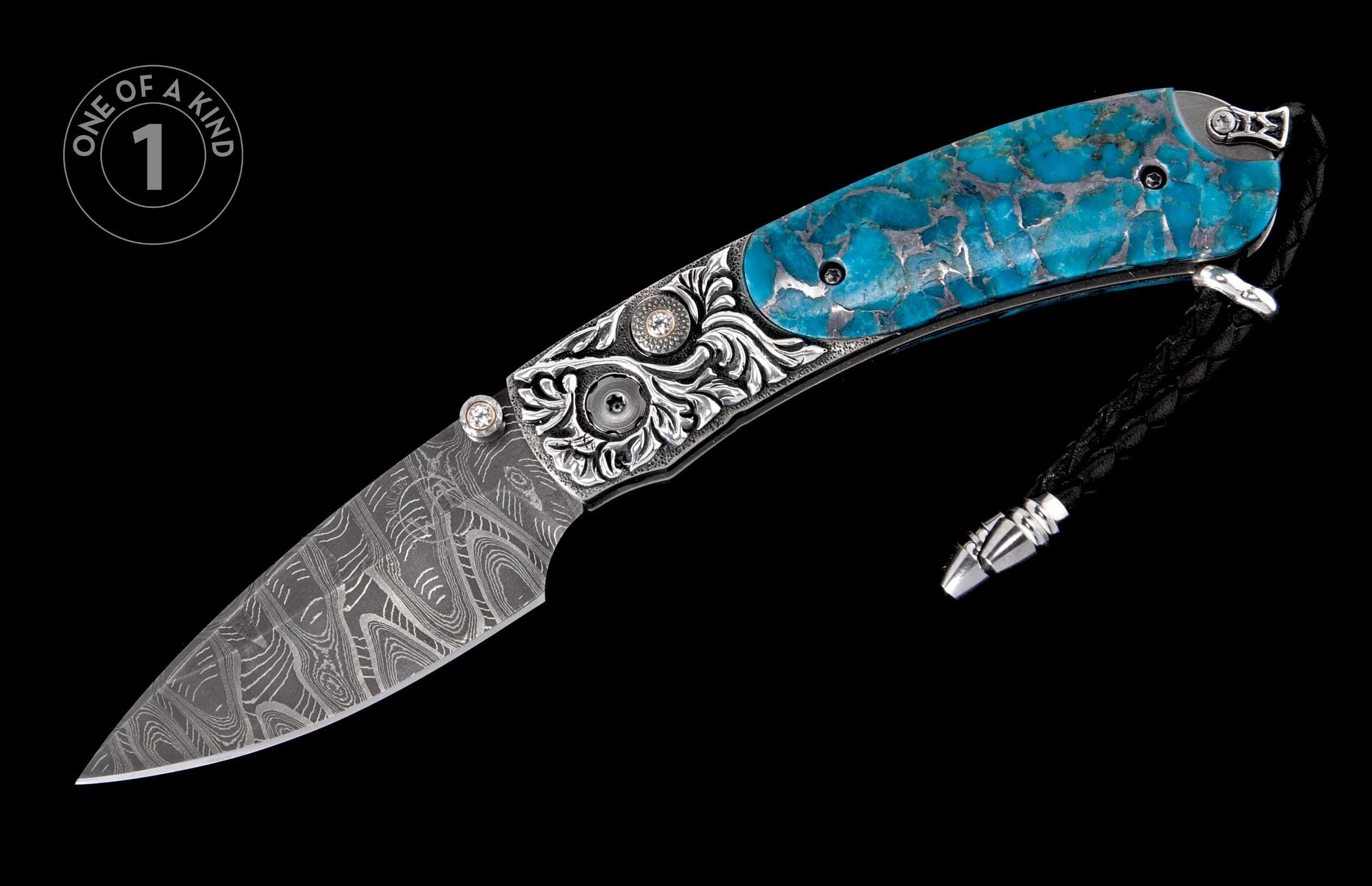 A custom folding knife with a Damascus blade, bright turquoise inlays, intricate silver engraving, and a black braided leather lanyard.
