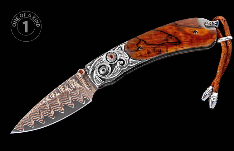 Ornate folding knife with a dark wood handle, silver scrollwork, red gemstones, and a patterned Damascus steel blade, with a braided leather lanyard.