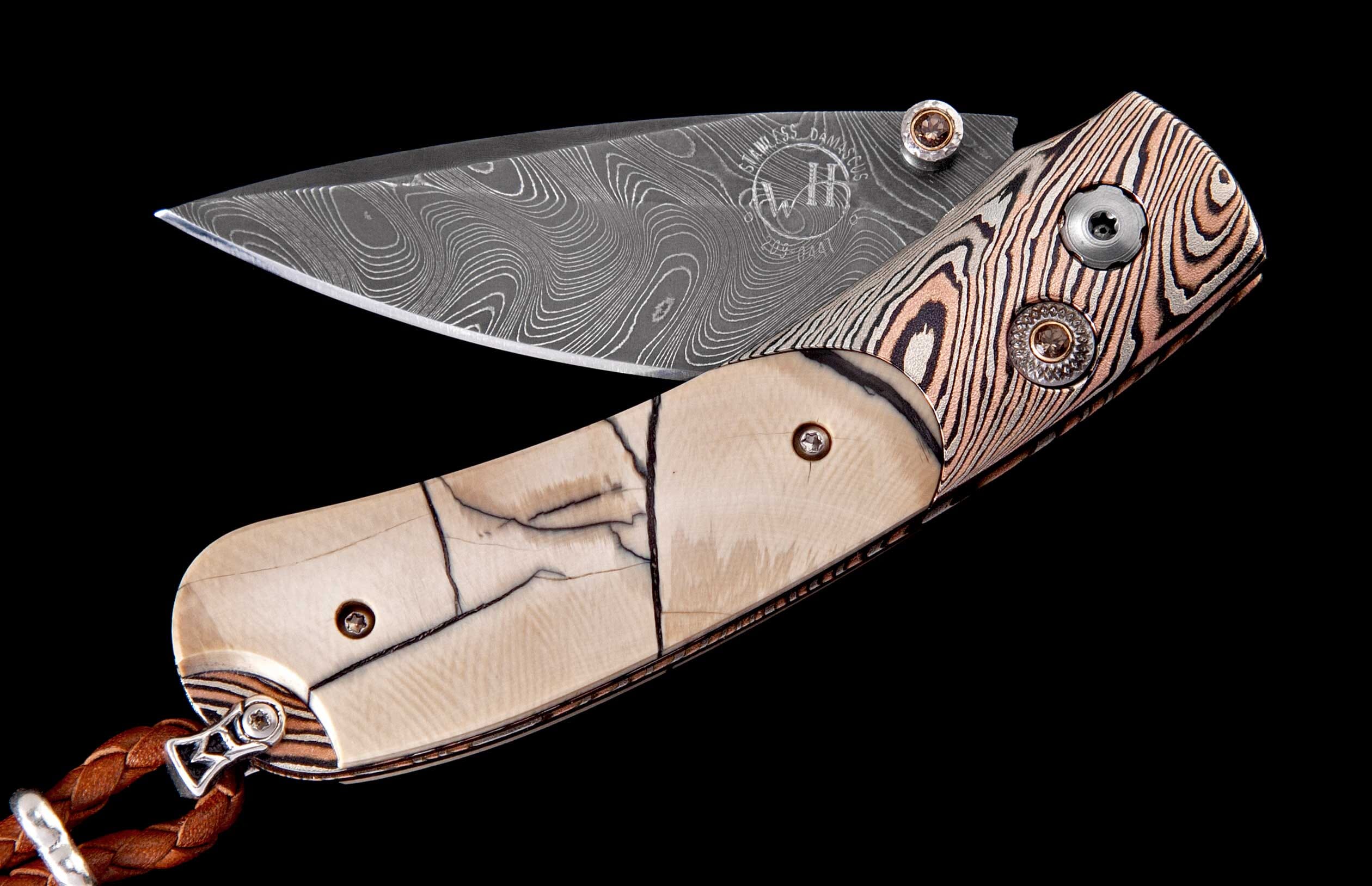 Damascus steel folding knife with ivory and patterned copper handles, partially open, featuring a visible logo and a braided leather lanyard on a black background.
