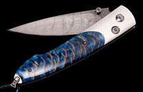 Folding knife with a Damascus steel blade featuring a 'WH' logo, a blue and orange fish scale handle, and blue gemstone accents.
