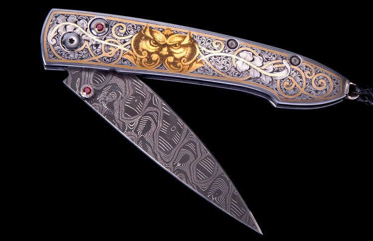 Ornate folding knife with an intricately engraved silver and gold handle featuring an owl motif and red gemstones, alongside a patterned Damascus steel blade.