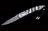 Folding knife with a patterned Damascus blade, engraved silver bolster, and a striped handle of white, blue, and brown, with a black braided lanyard.