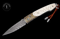 Ornate folding knife with a swirling Damascus blade, carved white handle, gold engraved bolster, and brown leather lanyard.