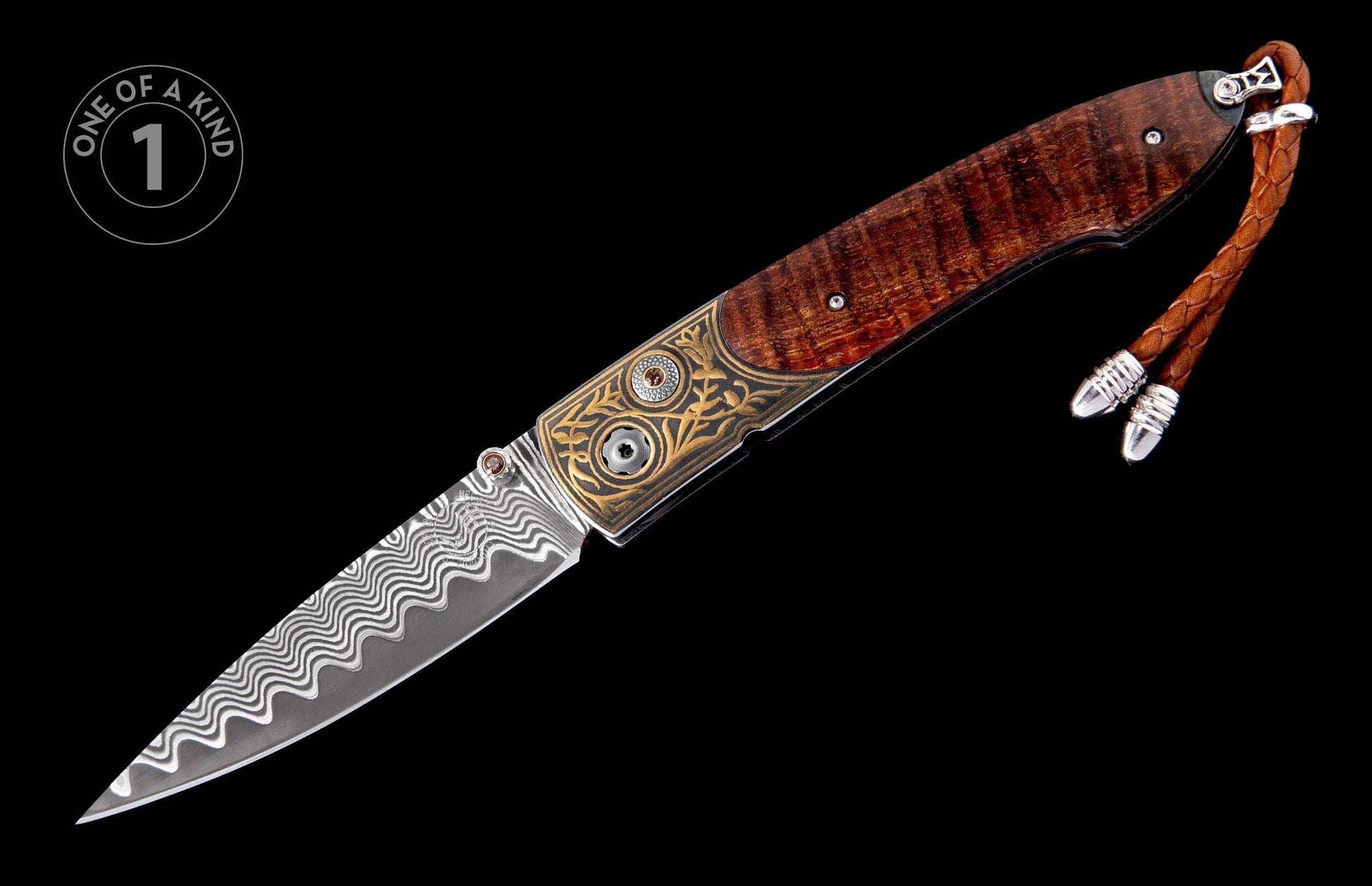 Folding knife with a wavy Damascus blade, ornate gold-engraved handle, rich figured wood, brown stone accents, and a braided leather lanyard.
