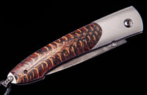 Custom folding knife with a red and tan pinecone handle, a silver bolster, and a visible Damascus steel spine.