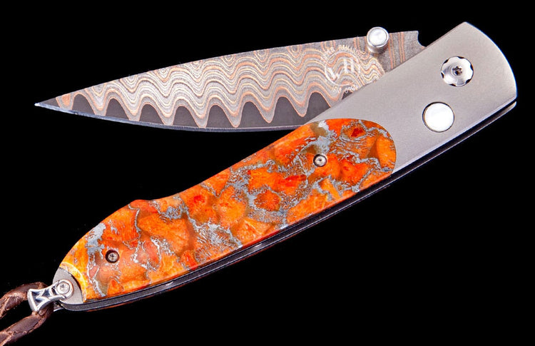 Folding knife with a wavy Damascus steel blade and an orange and silver mottled handle.