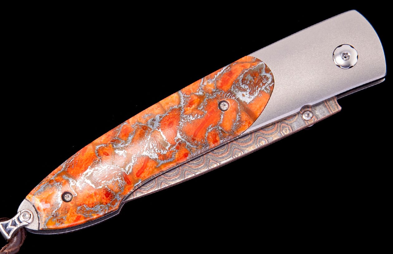 Folding knife with a vibrant orange and silver marbled handle, featuring a textured copper-toned spine.
