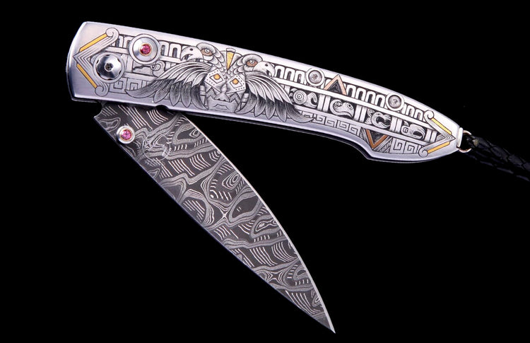 Silver-toned folding knife with intricate eagle and geometric engravings, gold accents, red gemstones, and a swirling patterned Damascus-style blade.