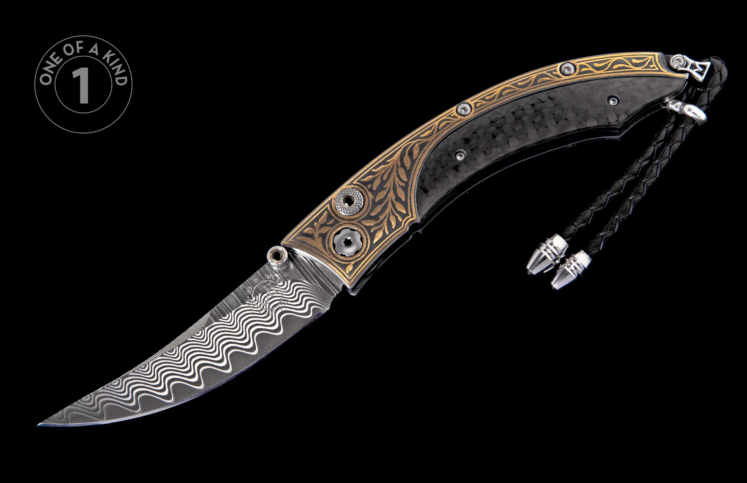 Ornate folding knife with a wavy Damascus blade, gold engraved metal handle, black carbon fiber, and braided lanyard.