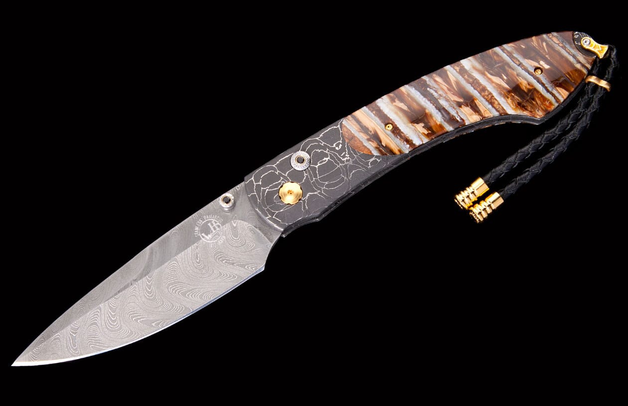 Elegant folding knife with a Damascene blade, brown striped handle, a dark patterned bolster, and a black braided lanyard with gold accents.
