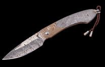 Damascus folding knife by Carefree Buffalo with patterned meteorite handle, gold accents, and braided leather lanyard.