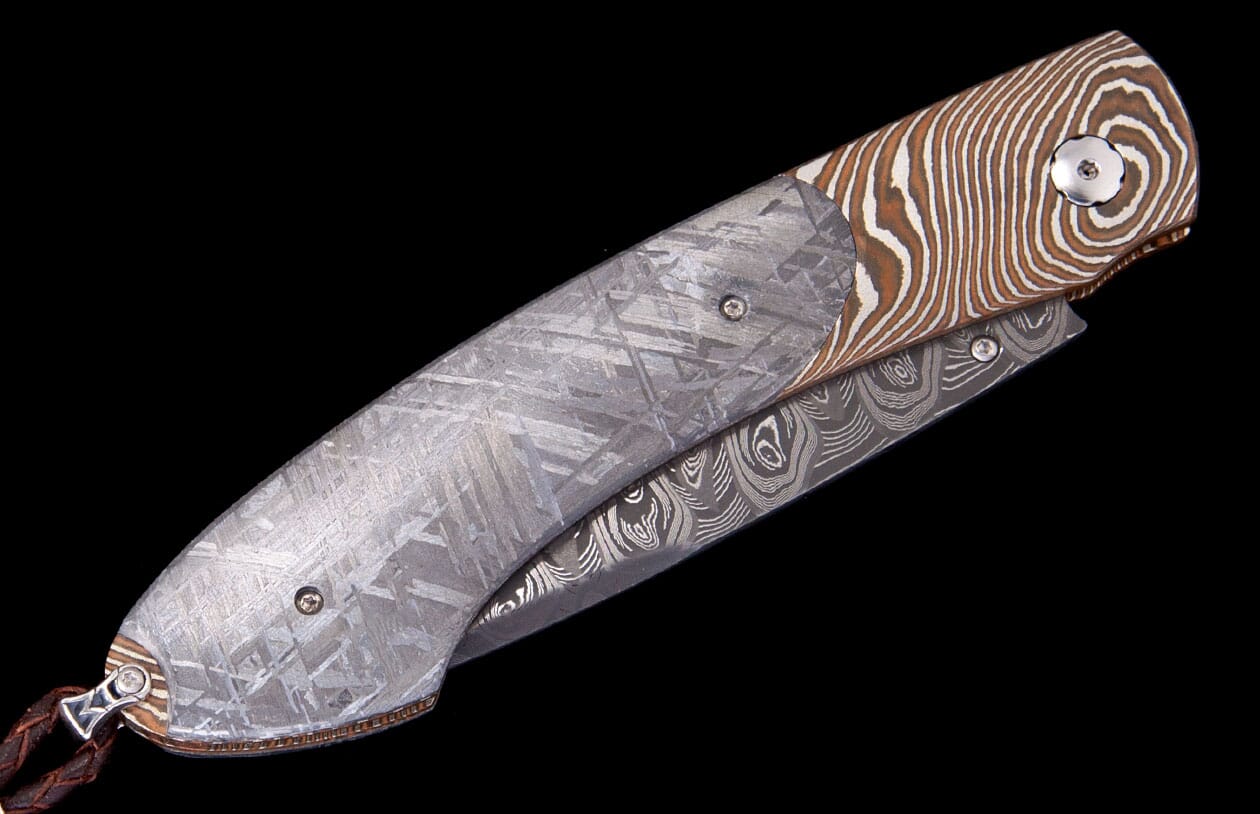 Meteorite and Damascus steel folding knife by Carefree Buffalo, featuring distinct crystalline and wavy patterns.