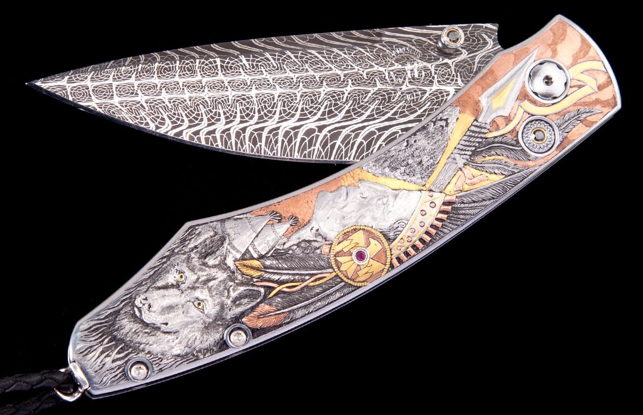 Highly decorative folding knife with a multi-metal engraved handle featuring a wolf, feathers, and mountains, and a swirling Damascus steel blade.