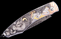 Intricately engraved folding knife with a wolf, horse, and man scene in multi-tone metal inlay, showcasing a Damascus patterned blade.