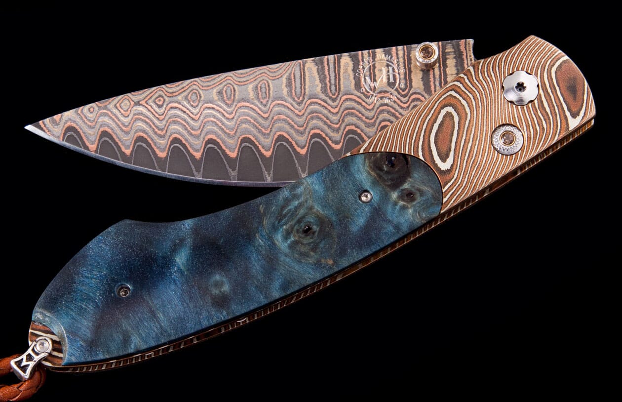Folding knife with a wavy copper Damascus blade and a handle featuring blue burled wood and brown swirled material.