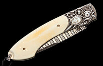 Creamy white handle knife with ornate silver bolster, skull motif, patterned metal, and black lanyard.