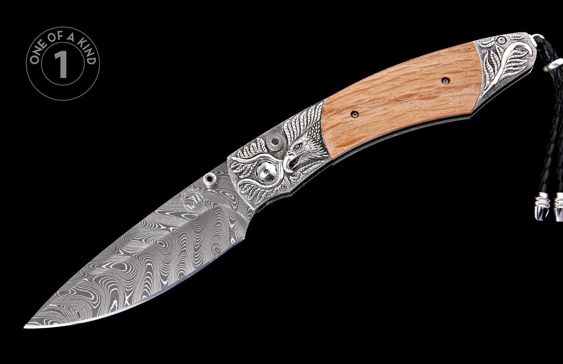 Open Damascus folding knife with wood handle, carved silver eagle bolsters, blue gems, and a braided black leather lanyard.
