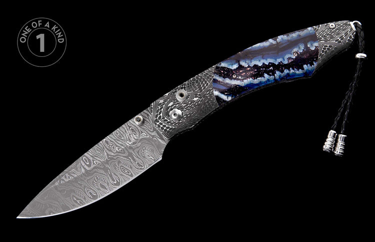 Knife with a Damascus patterned blade and a blue, purple, and white agate-like handle, with silver lanyard beads, displayed diagonally with a 'One of a Kind' label.