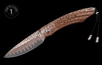 Damascus steel knife with brown and white swirling pattern, red gem inlays, silver accents, and a black leather lanyard.