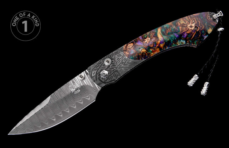 A folding knife with a wavy Damascus steel blade, a multi-colored resin handle with abstract floral patterns, and a black lanyard.